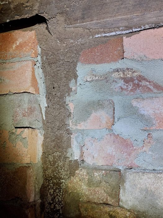 Termite mud tracks on brick foundation pier — active infestation